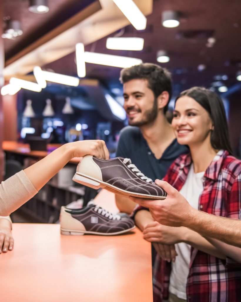 Cheerful young people are taking bowling shoes and smiling ready to play bowling